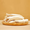 A wooden plate full of Freeze-Dried Chicken Breast tenders from Arya! Sit. Side view of tenders stacked high. 4"-5" long tenders are whole, not in pieces.