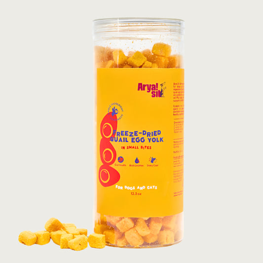 12.3 oz clear plastic container of Arya! Sit Freeze-Dried Quail Egg Yolk in Small Bites for Dogs & Cats. Gut health, rich in Lecithin, shiny coat. Product inside is visible; they are small pale orange cubes.
