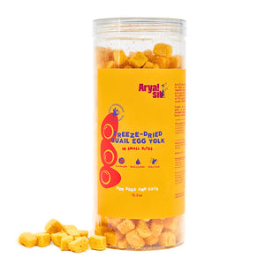 12.3 oz clear plastic container of Arya! Sit Freeze-Dried Quail Egg Yolk in Small Bites for Dogs & Cats. Gut health, rich in Lecithin, shiny coat. Product inside is visible; they are small pale orange cubes.