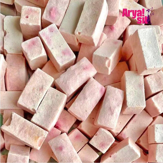 Super closeup view of Arya! Sit Freeze-Dried Strawberry Yogurt bites. They are pale pink, square to rectangular shaped cubes, about 1/2" to 1" long.