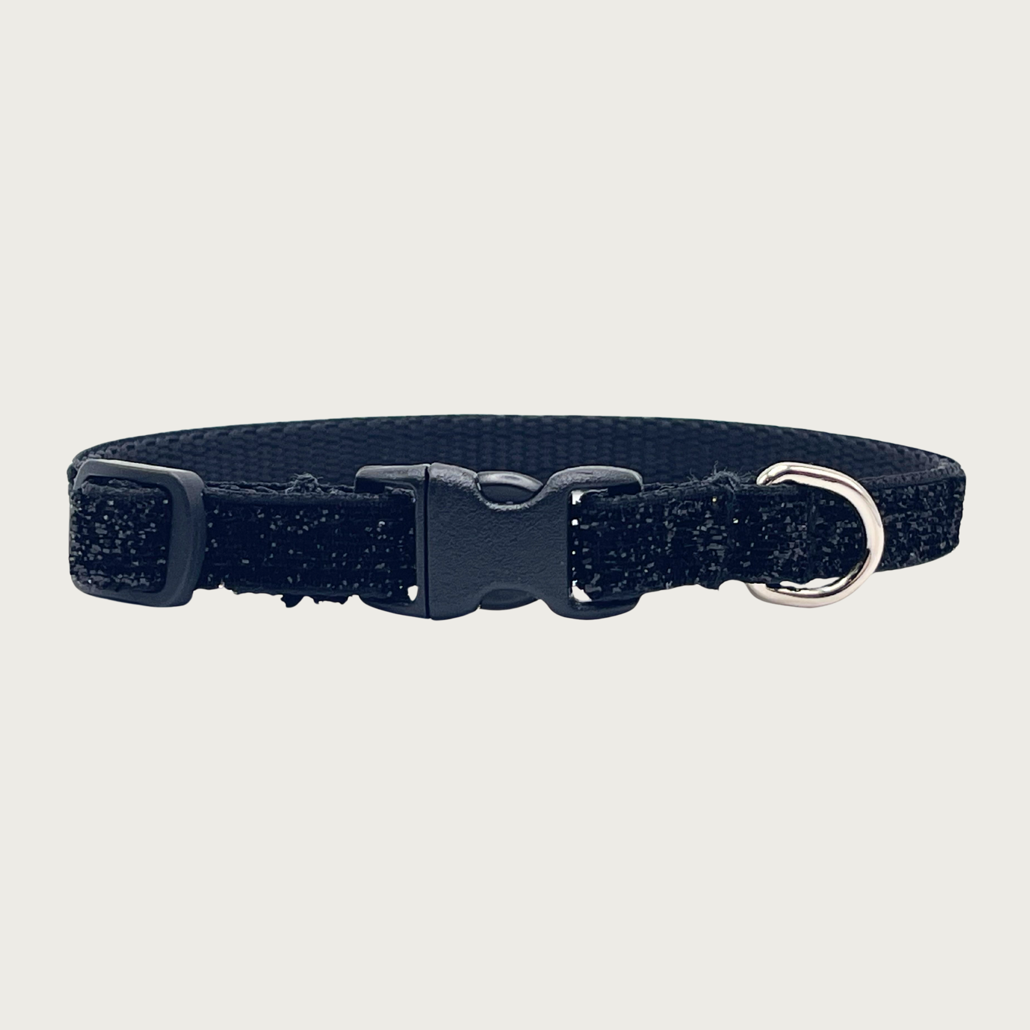 Skinny, black hued glitter teacup dog collar with a small silver D-ring, black nylon inner webbing and black plastic buckle. The fabric itself is shimmery & glittery - it is not glued on.