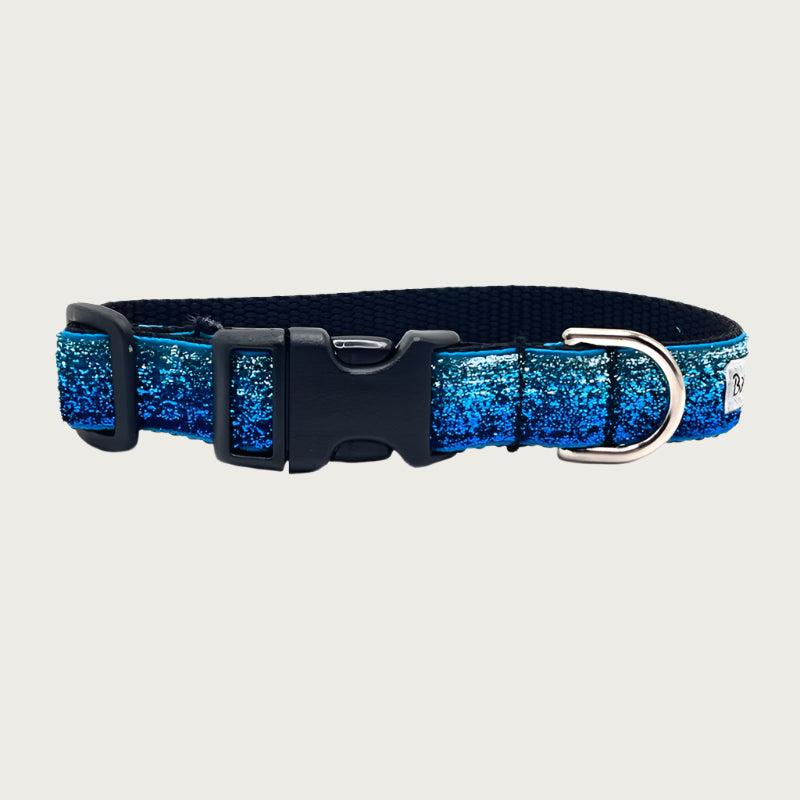 Blue gradient (light blue to deep blue) hued glitter 3/4" wide dog collar with a D-ring, black nylon inner webbing and black plastic buckle. The fabric itself is shimmery & glittery - it is not glued on.
