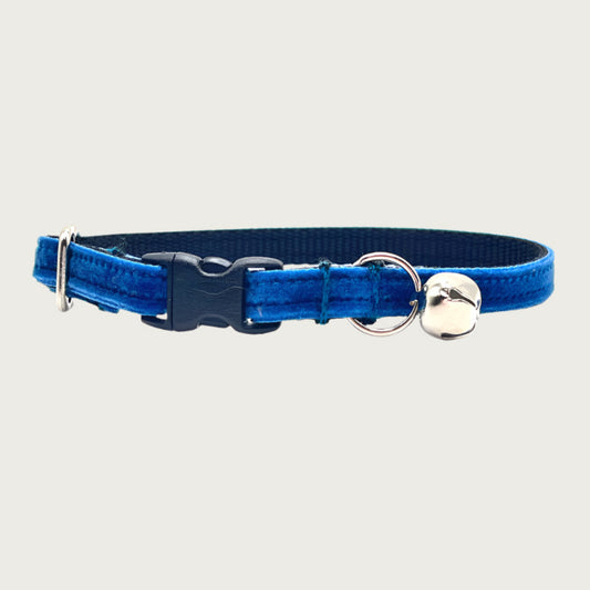 Royal blue hued velvet cat collar with a silver bell and small D-ring. Black nylon inner webbing and black plastic buckle.