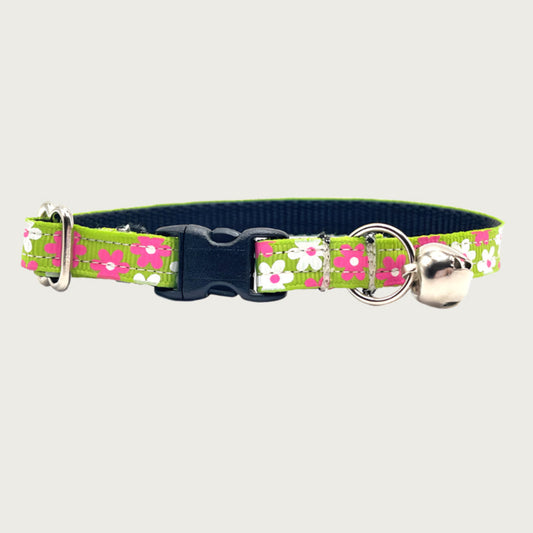 Lime green cat collar with simple hot pink and white flowers. Has a silver bell and small D-ring. Black nylon inner webbing and black plastic buckle.
