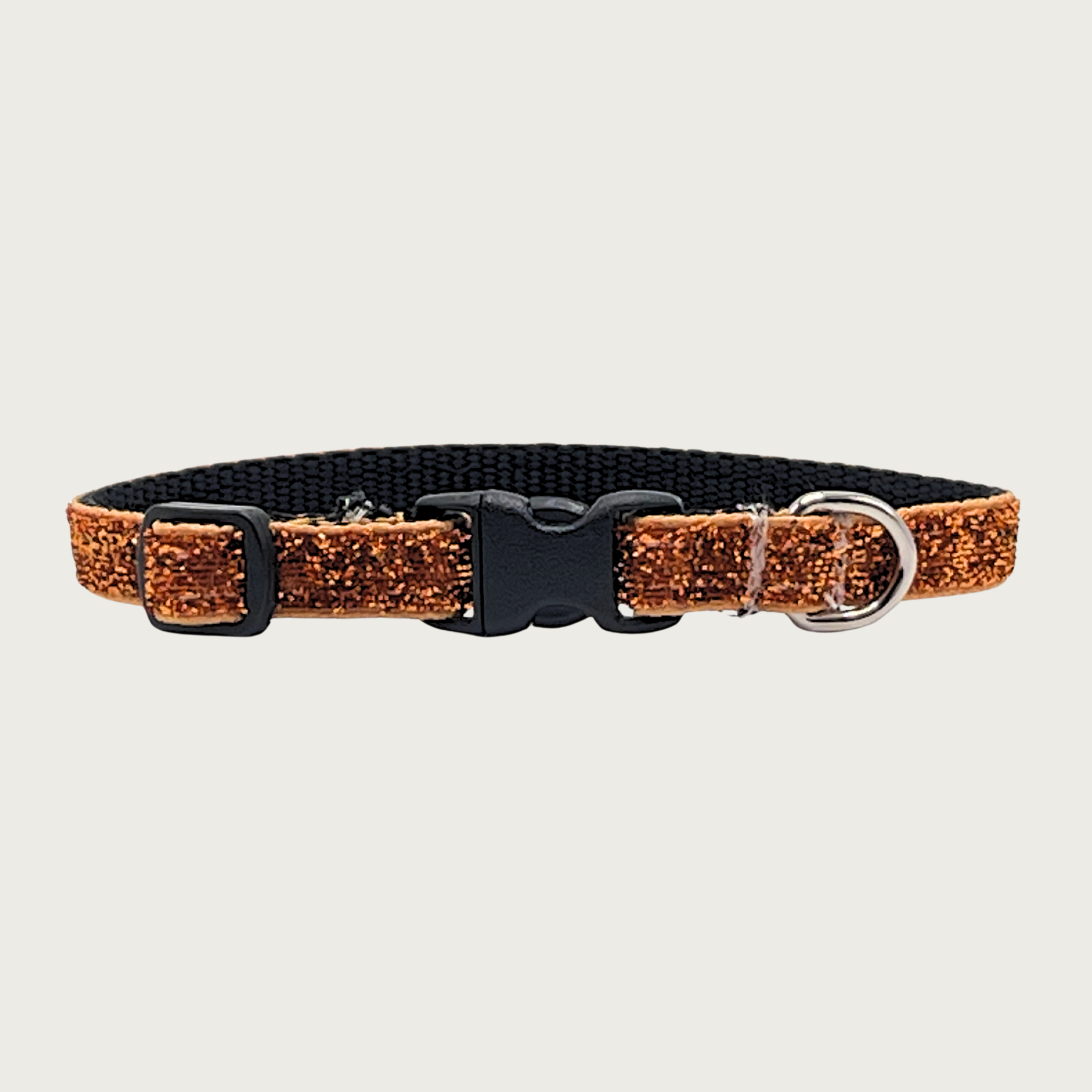 Skinny, orange (melon) hued glitter teacup dog collar with a small D-ring, black nylon inner webbing and black plastic buckle. The fabric itself is shimmery & glittery - it is not glued on.