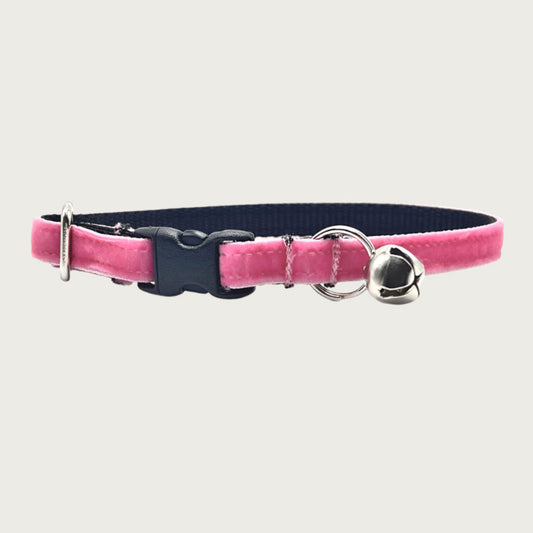 Medium-pink hued velvet cat collar with a silver bell and small D-ring. Black nylon inner webbing and black plastic buckle.