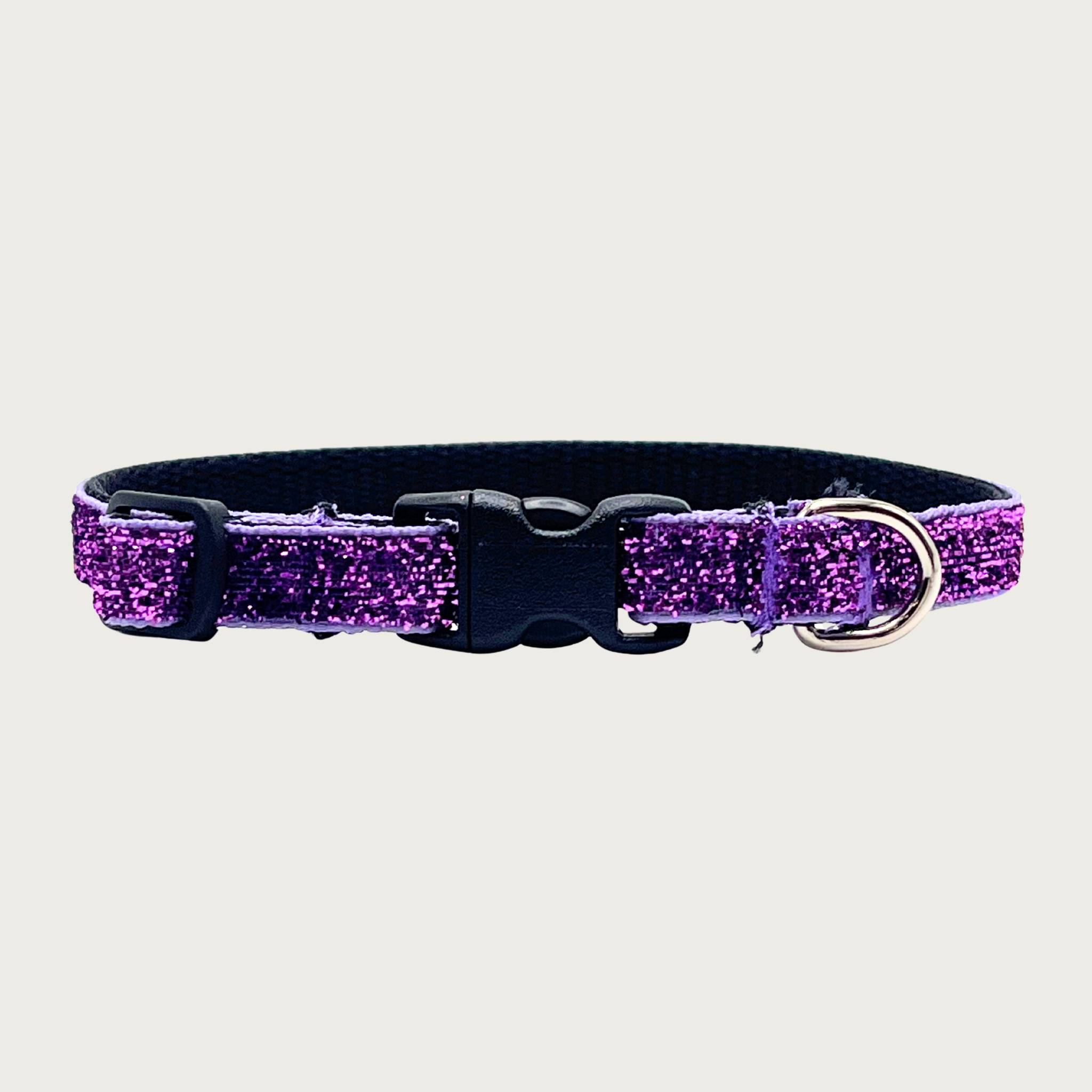 Skinny, deep purple hued glitter teacup dog collar with a small silver D-ring, black nylon inner webbing and black plastic buckle. The fabric itself is shimmery & glittery - it is not glued on.