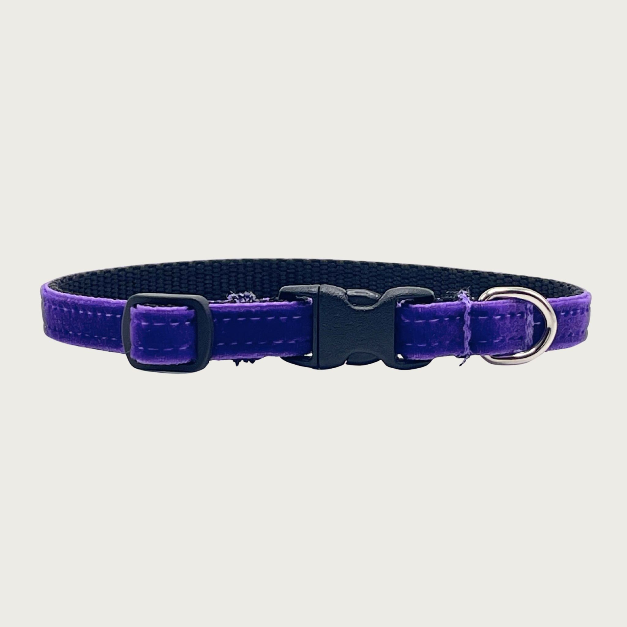 Skinny, deep purple hued velvet teacup dog collar with a small D-ring, black nylon inner webbing and black plastic buckle.
