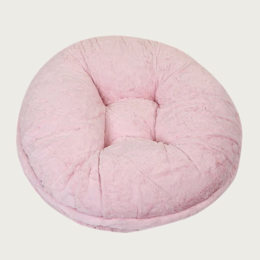 Round, pale pink colored plush pet bed with faux mink fur.