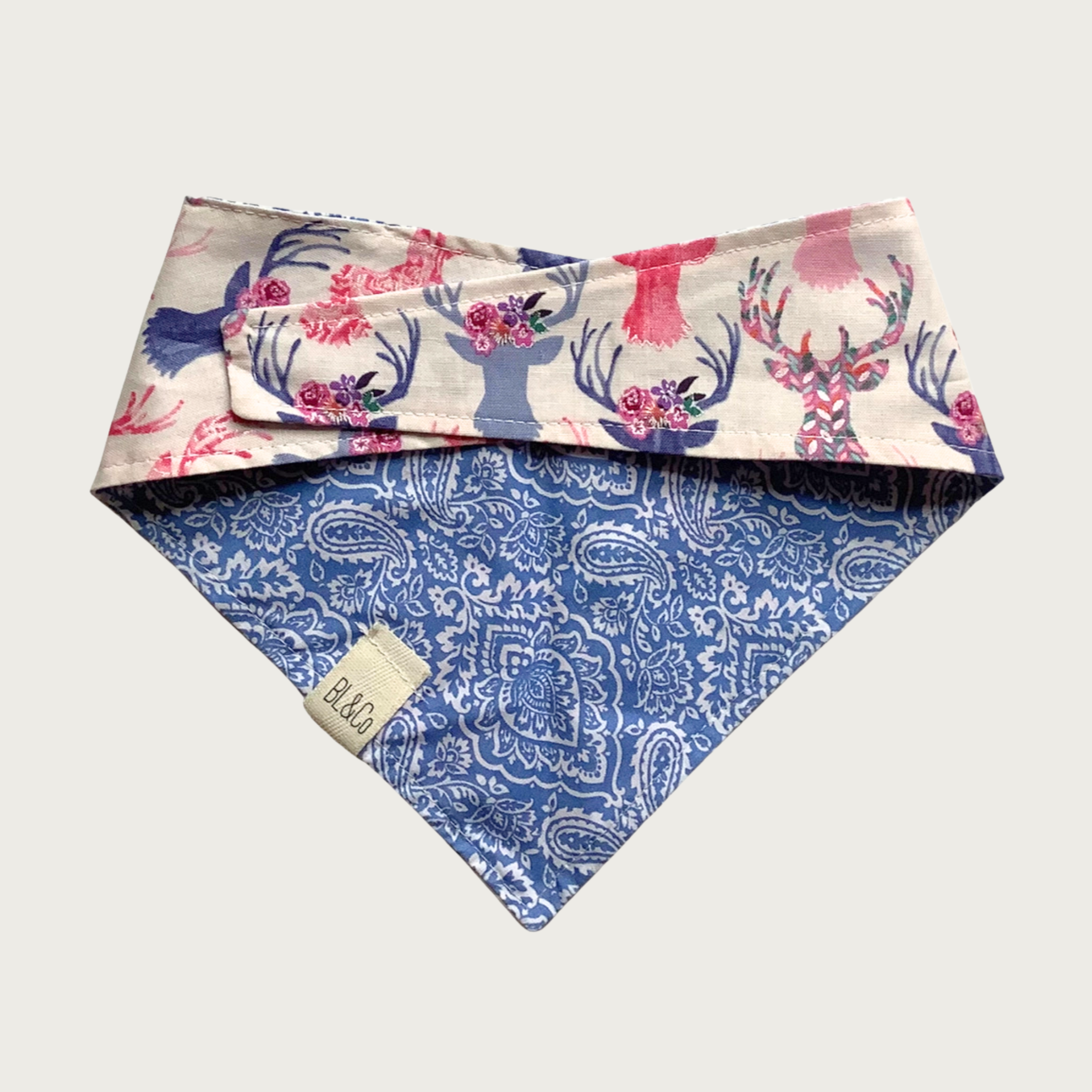 Reverse view of the dog bandana with delicate blue & white paisley pattern on top, and blue & pink pastel floral deer silhouette pattern.