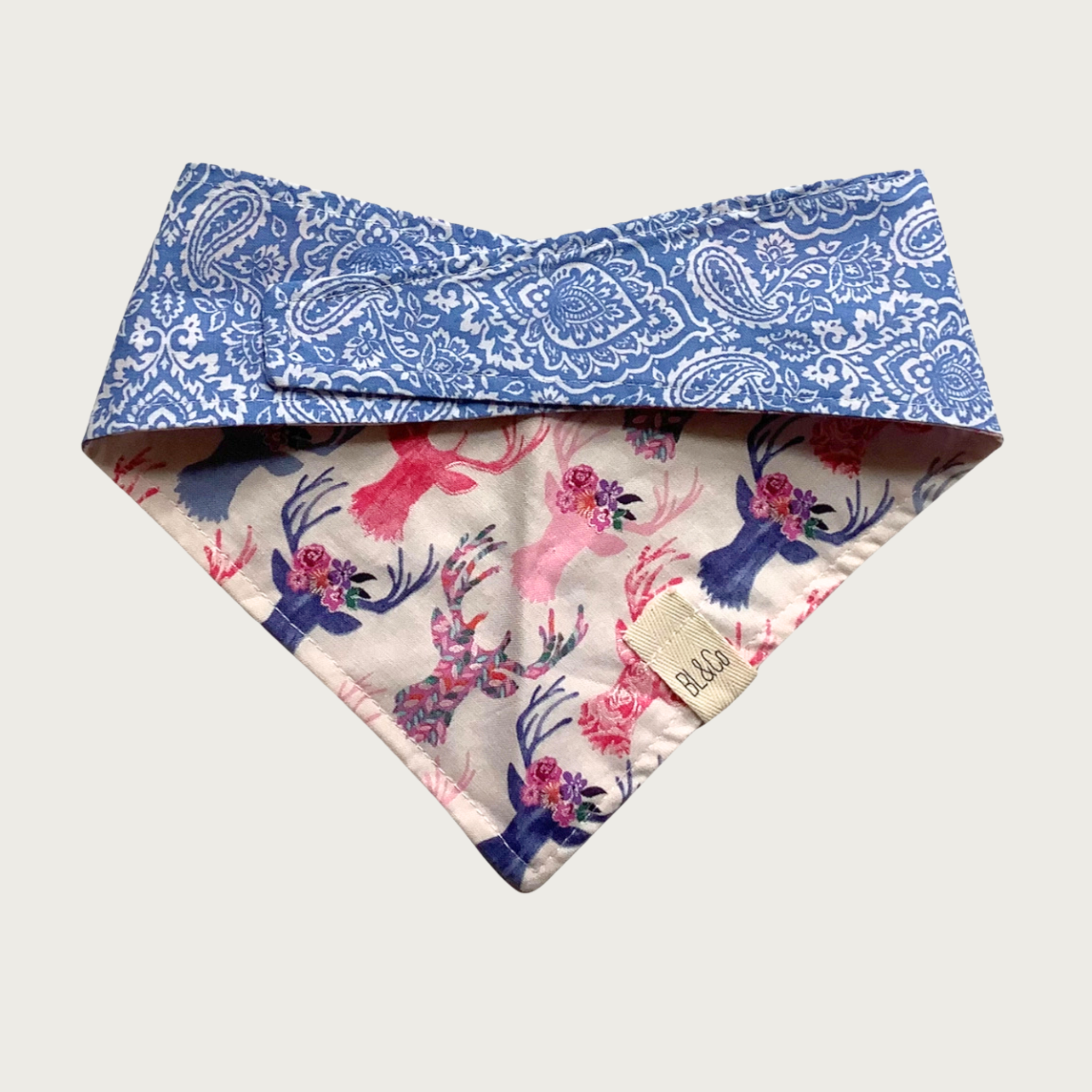 Dog bandana with delicate blue & white paisley pattern on top, and blue & pink pastel floral deer silhouette pattern on the reverse.