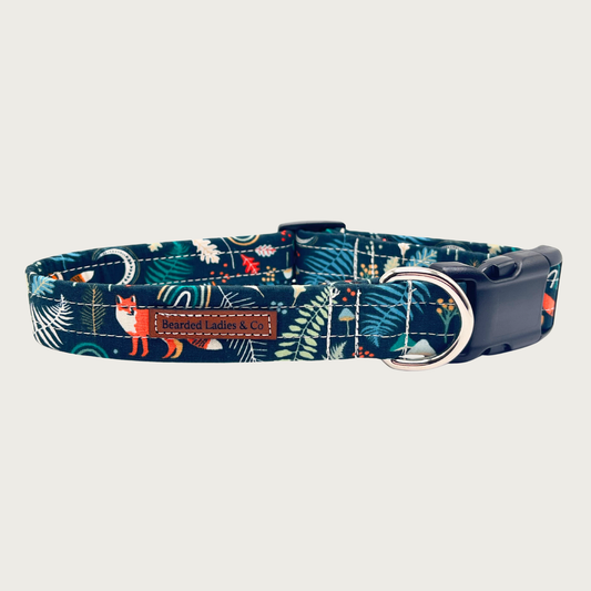 Deep navy blue dog collar with multicolored fox and leaf pattern, with black plastic hardware and silver metal D-ring. 