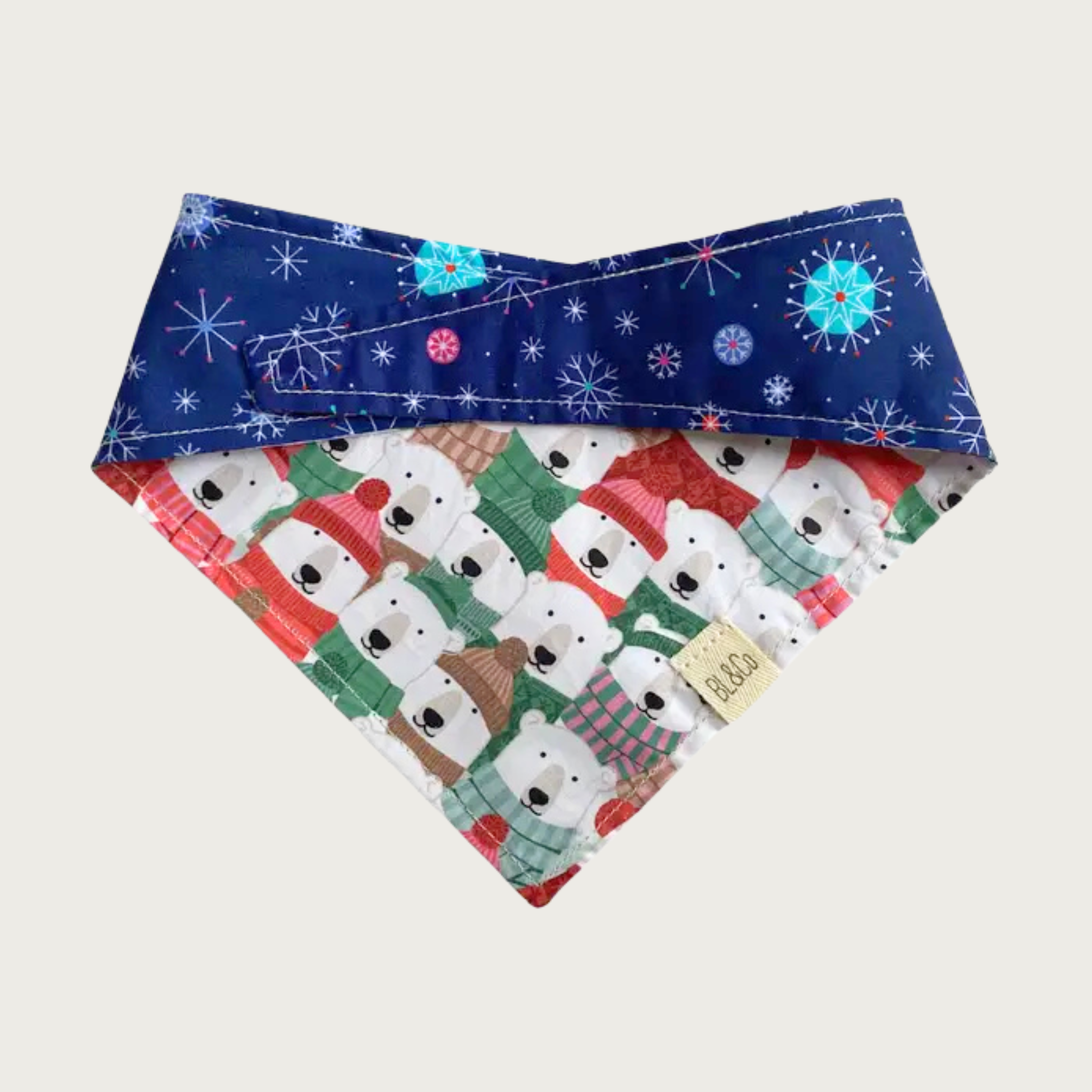 Dog bandana with deep blue & delicate multicolor snowflake pattern on top, and polar bears wearing hats, scarves & sweaters on the reverse.