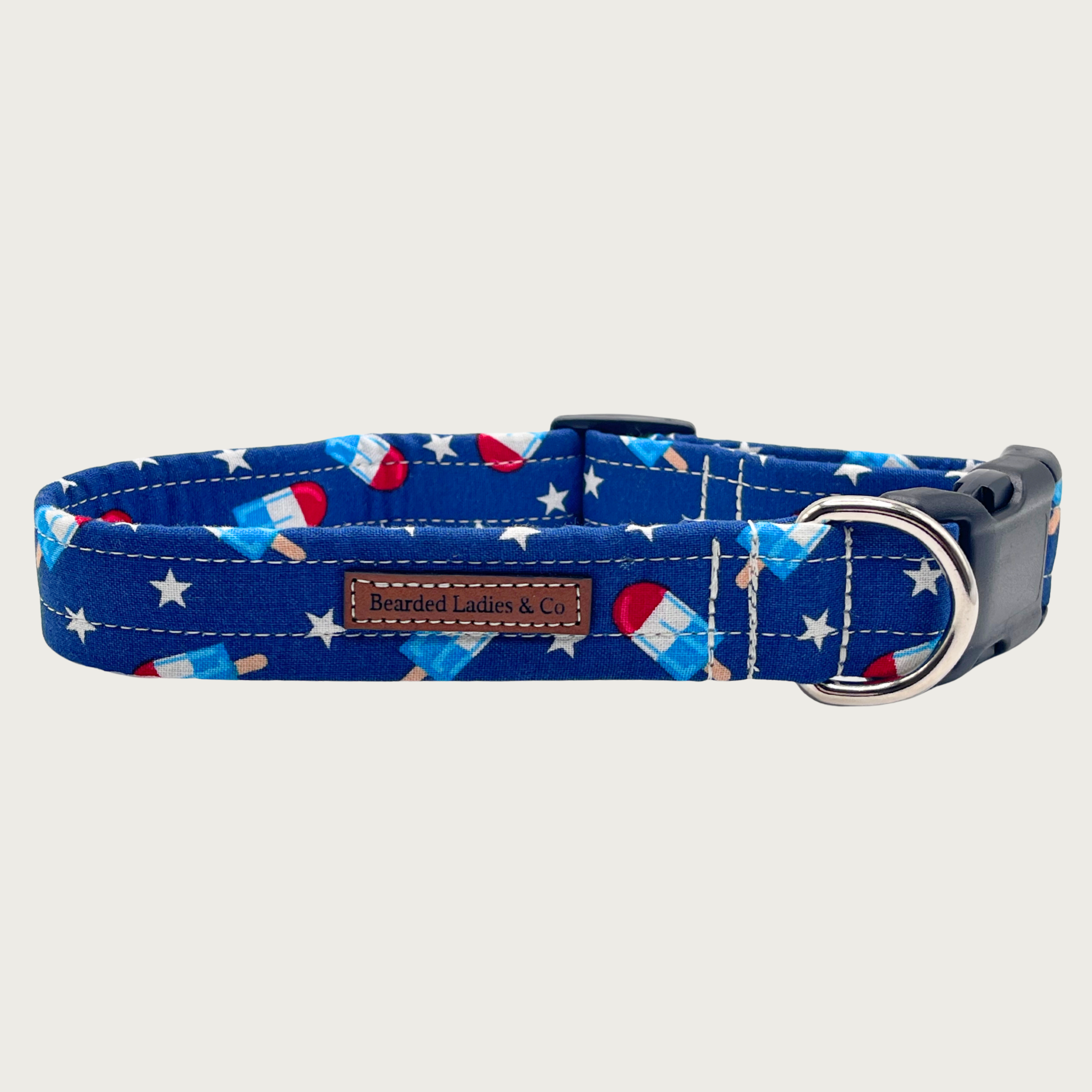 Deep royal blue dog collar with a bomb pop popsicle (red, white, and bright blue) and white star pattern. Black plastic hardware and silver metal D-ring.