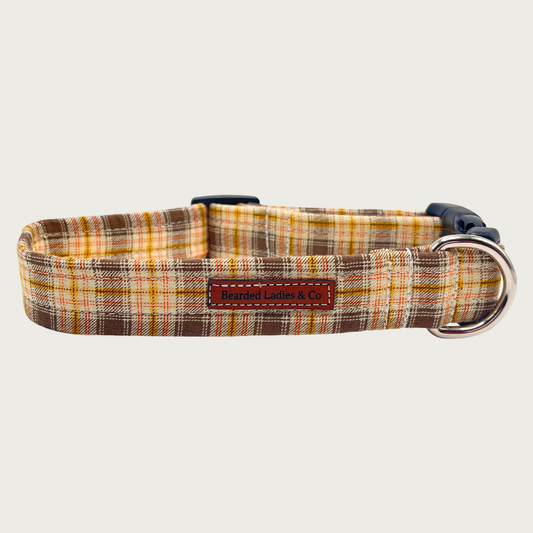 Medium brown, cream, yellow, and orange plaid dog collar with black plastic hardware and silver metal D-ring.