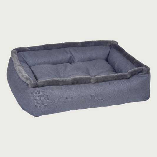 Charcoal gray/deep navy colored, rectangular pet bed with dark gray faux fur trim on top edges. 