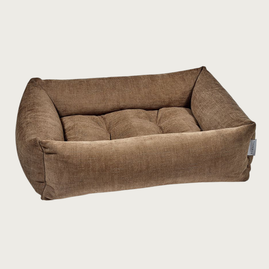 Caramel (medium reddish brown) colored, rectangular pet bed with bolsters & tufted center cushion. It has a slightly textured, stonewashed appearance.