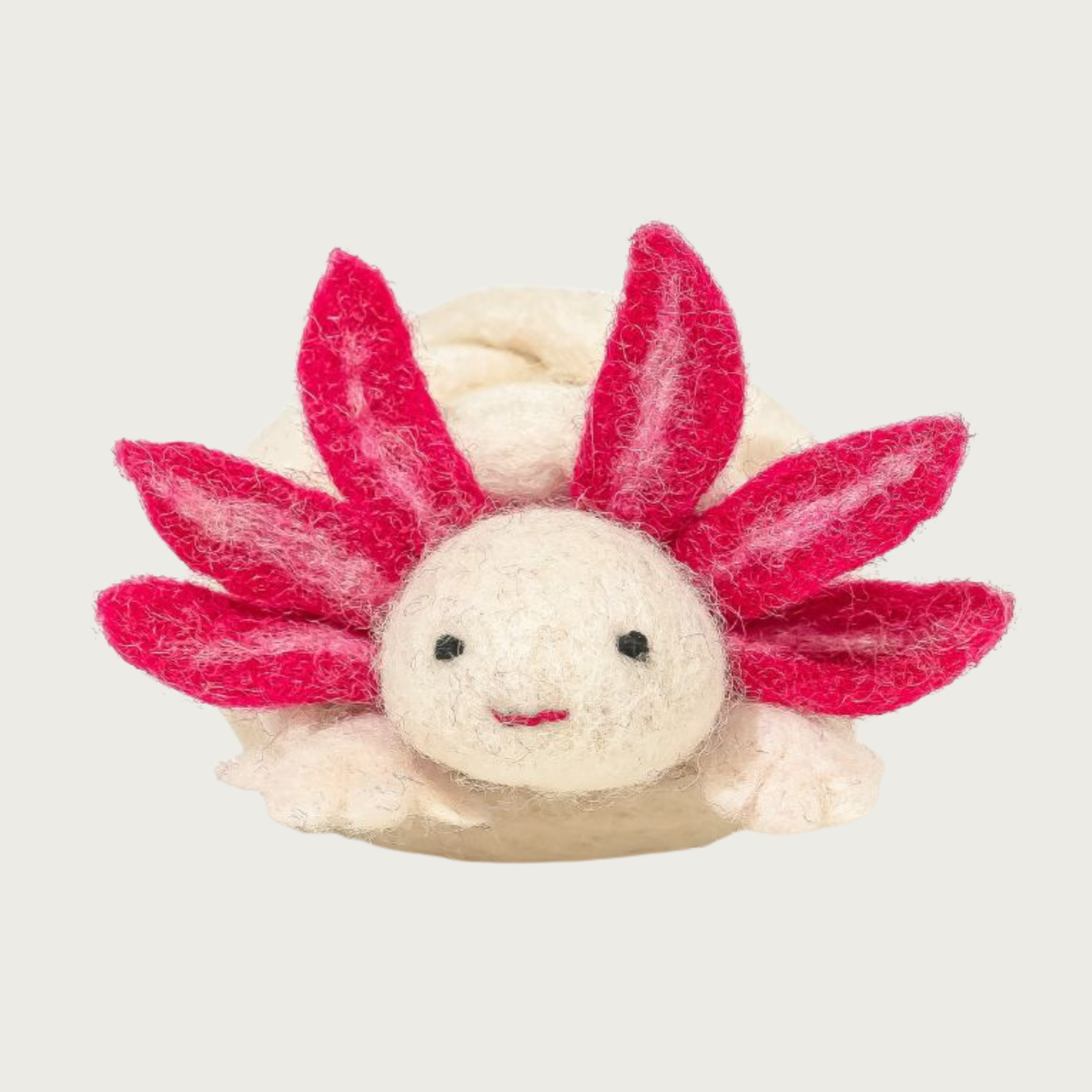 Front view of the wool axolotl cat toy. Its body is cream colored, with red & pink gills that look like large sunflower petals around its face, which has a simple, embroidered smile. 