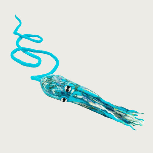 Wool octopus toy laying on its side, with its legs directly beneath it (vs. splayed out), to show their length. 