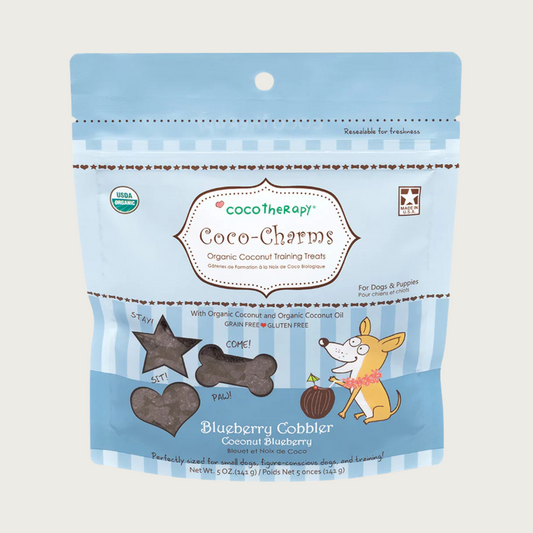 5 oz blue bag of CocoTherapy Coco-Charms Blueberry Cobbler organic coconut training treats for dogs. Made with coconut & coconut oil. Grain-free, gluten free. USDA organic, made in USA. Treats visible through 3 clear windows are tiny (smaller than a dime) and dark colored, and in three shapes: hearts, stars and bones.