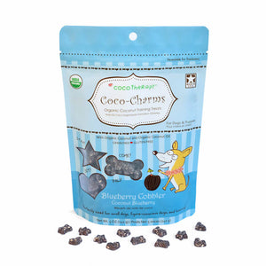 5 oz blue bag of CocoTherapy Coco-Charms Blueberry Cobbler organic coconut training treats for dogs. Made with coconut & coconut oil. Grain-free, gluten free. USDA organic, made in USA. Sample of treats in front of bag are tiny (smaller than a dime) and dark colored, and in three shapes: hearts, stars and bones.