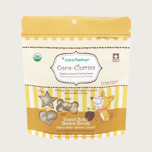 5 oz tan bag of CocoTherapy Coco-Charms Peanut Butter Banana Blondie organic coconut training treats for dogs. Made with coconut & coconut oil. Grain-free, gluten free. USDA organic, made in USA. Treats visible through 3 clear windows are tiny (smaller than a dime) and tan colored, and in three shapes: hearts, stars and bones.