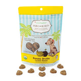 5 oz blue and yellow bag of CocoTherapy Pure Hearts Banana Brulee organic coconut dog treats. Made with coconut & coconut oil. Grain-free, gluten free. USDA organic, made in USA. Sample of treats in front of bag are brown, heart-shaped, and nickel sized.