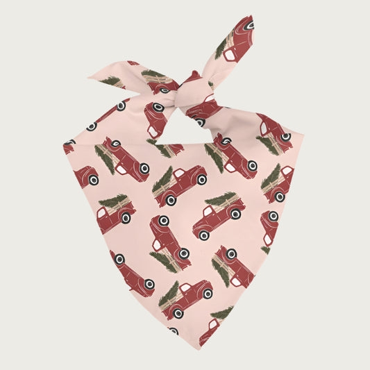 Dog bandana with red antique truck with a Christmas tree in its bed pattern on a pink background.