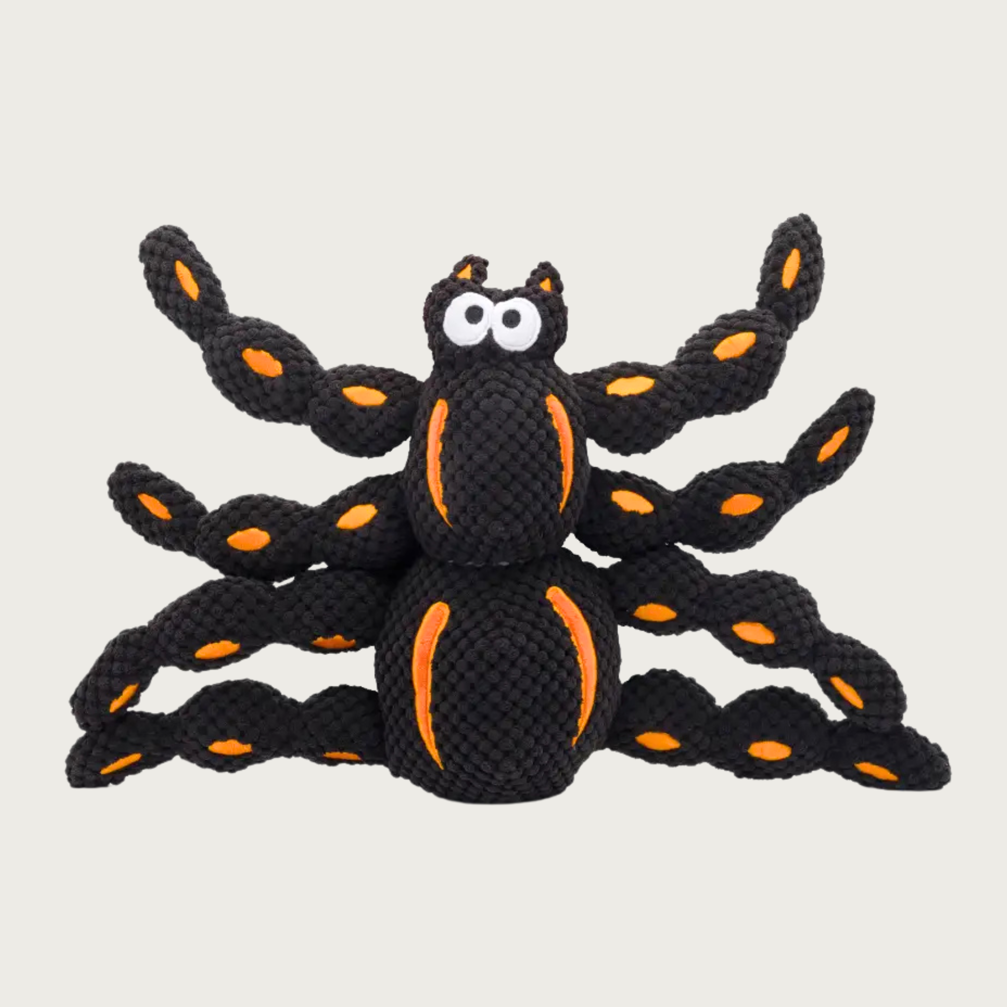 Black spider-shaped dog toy with orange accents on its body & legs and big eyes. Its body has a nubby, textured plush covering.
