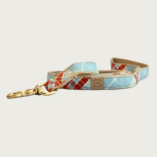 Dog leash with light blue base color, and criss-cross plaid pattern in cream and burnt orange.