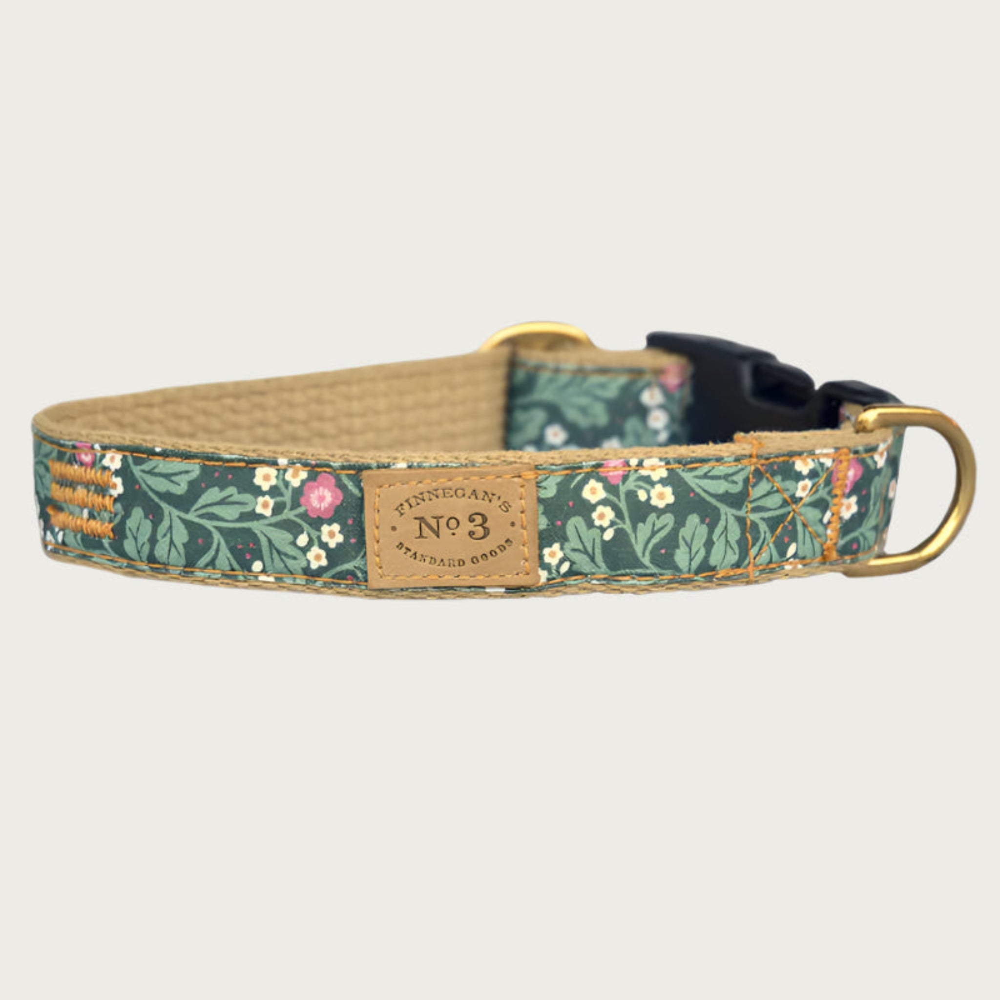 Dog collar with a botanical-themed print, in a base color of hunter green with small pink & white floral details with lighter green leaves. Black plastic buckle and brass D-ring.