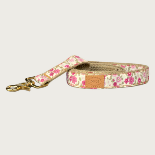 Dog leash with a multi-toned pink floral pattern on a pale yellow background, with a brass claw-style clip.