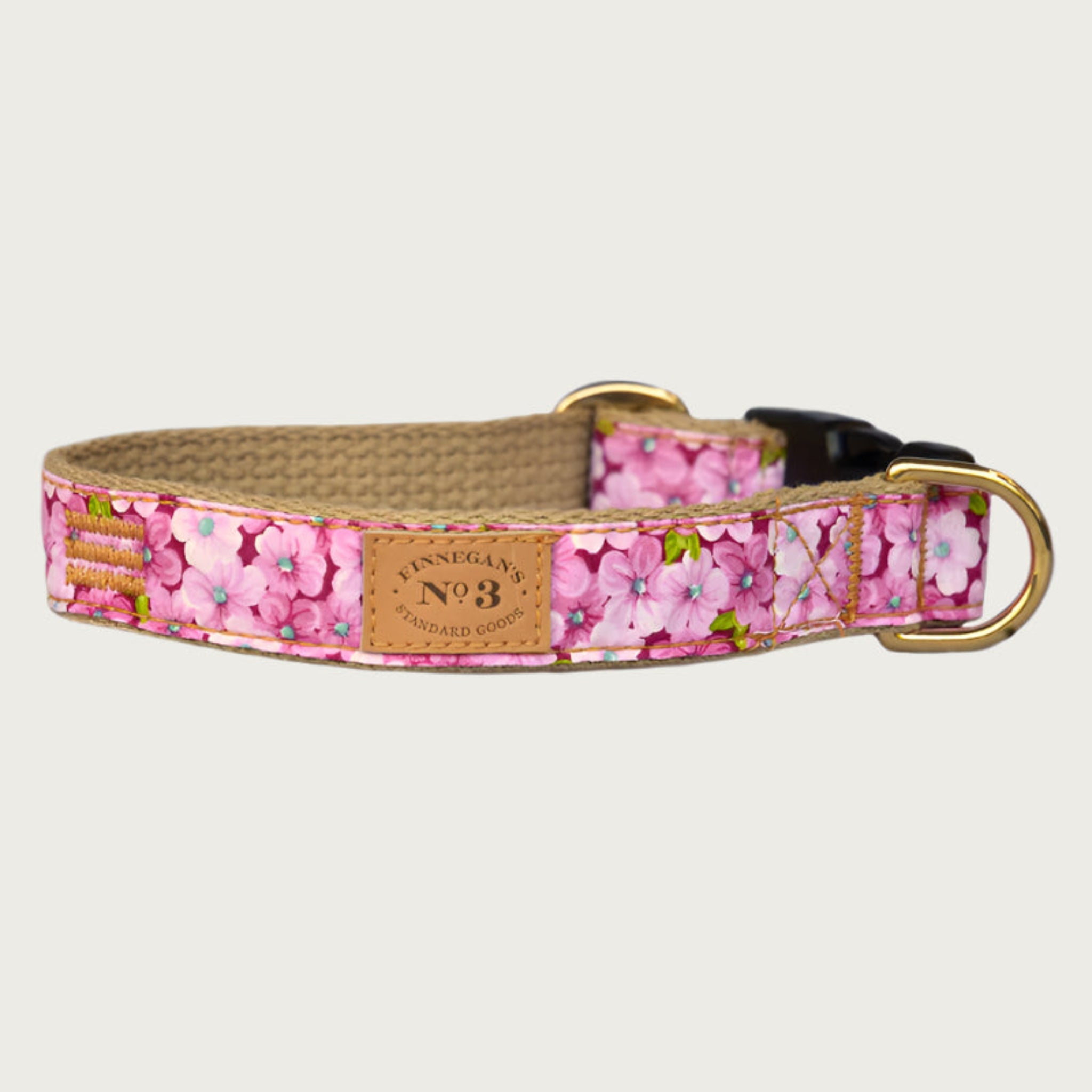 Dog collar with dense floral pattern in shades of pink, with a deep raspberry base color. Black plastic buckle and brass D-ring.