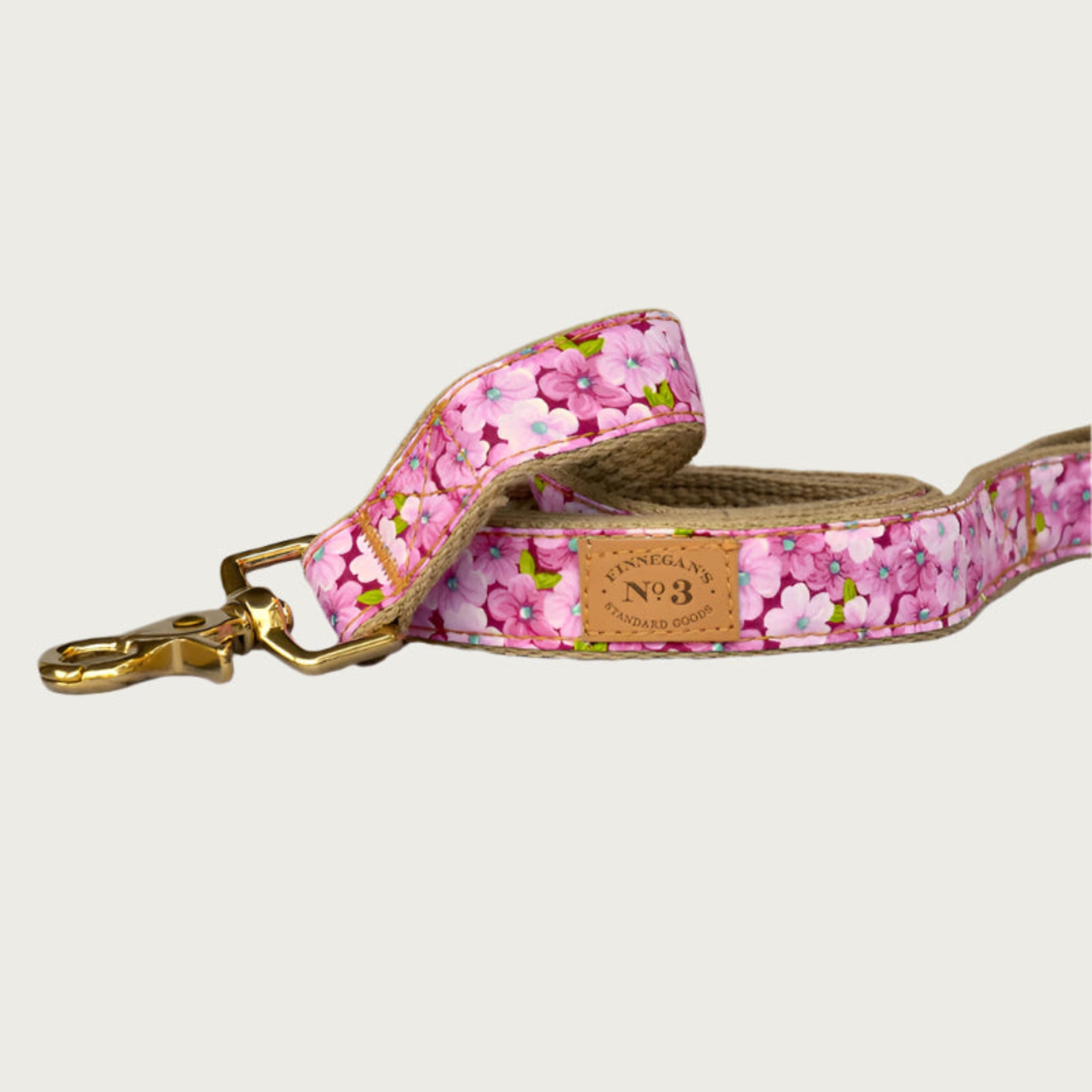 Dog leash with dense floral pattern in shades of pink, with a deep raspberry base color. Brass clasp.