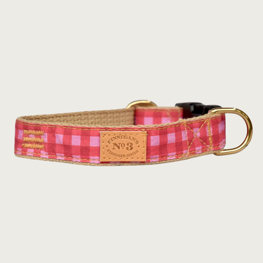 Dog collar with classic gingham check pattern in three shades of rosy pink, with tan cotton underside. Has brass hardware and a black plastic buckle.