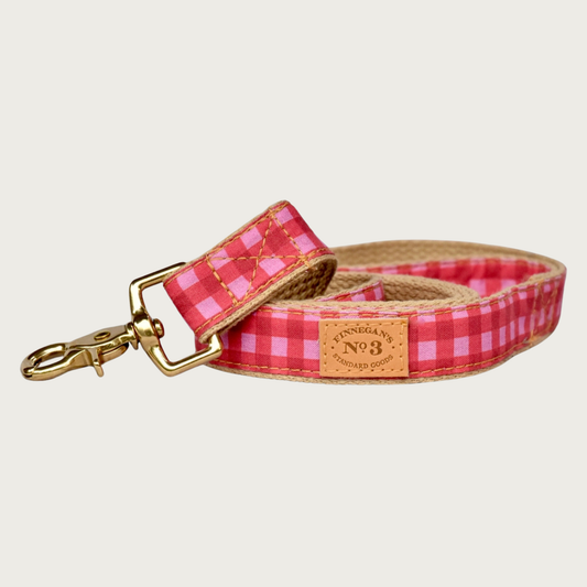Dog leash with classic gingham check pattern in three shades of rosy pink, with tan cotton underside. Has brass claw-style clip.