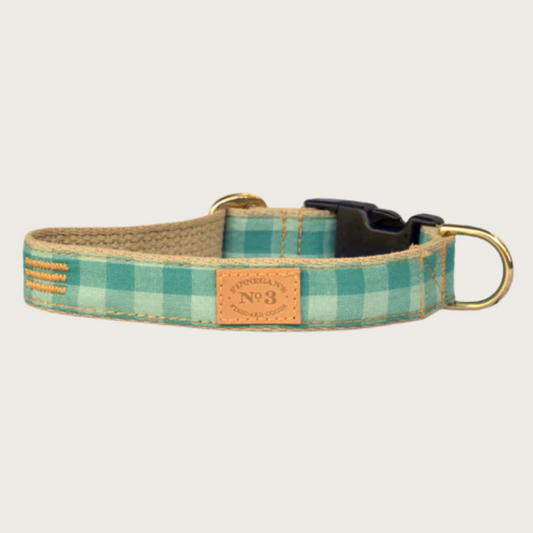 Dog collar with wide-checkered pattern in three shades of teal green, with a brass D-ring and black plastic buckle.