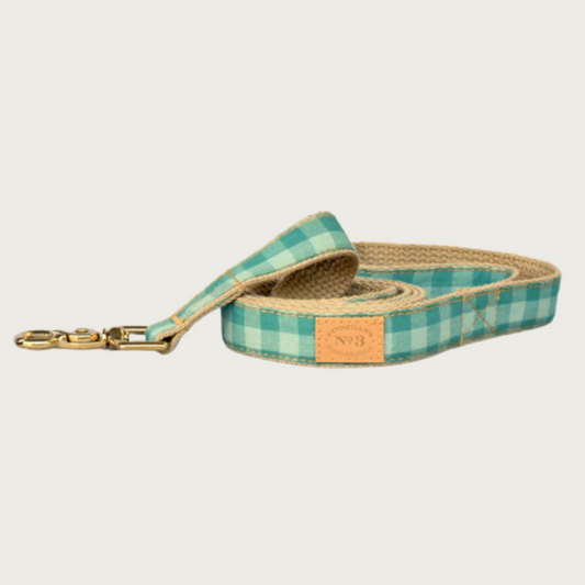 Dog leash with wide-checkered pattern in three shades of teal green with brass claw-style clip.