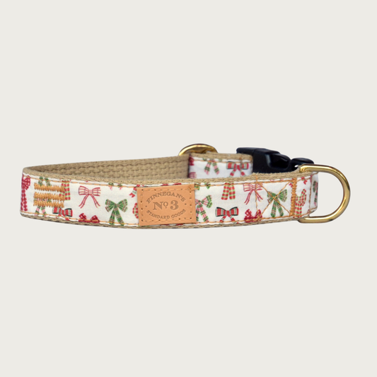 Christmas-themed dog collar featuring gift bows in various holiday colors and patterns, in shades of red and green, on a creamy white background.