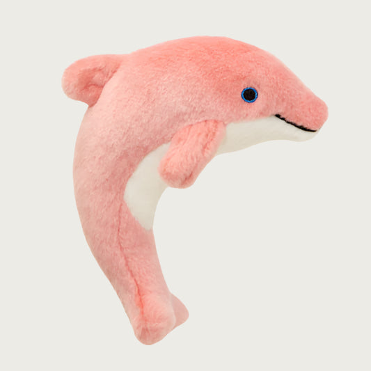 Pale coral pink plush Gisele Mini Dolphin dog toy from Fluff & Tuff. Toy is curved (like a dolphin in mid-leap) and has a white belly and blue eyes.