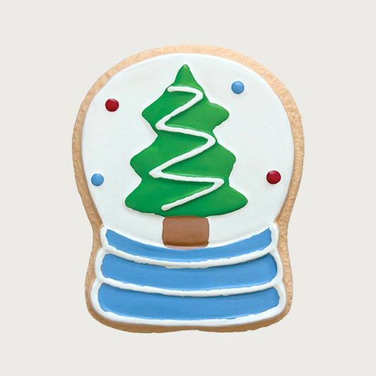 Flat, latex dog toy decorated to look like a sugar cookie. It's shaped like a snow globe with a Christmas tree on a white background, and blue base.
