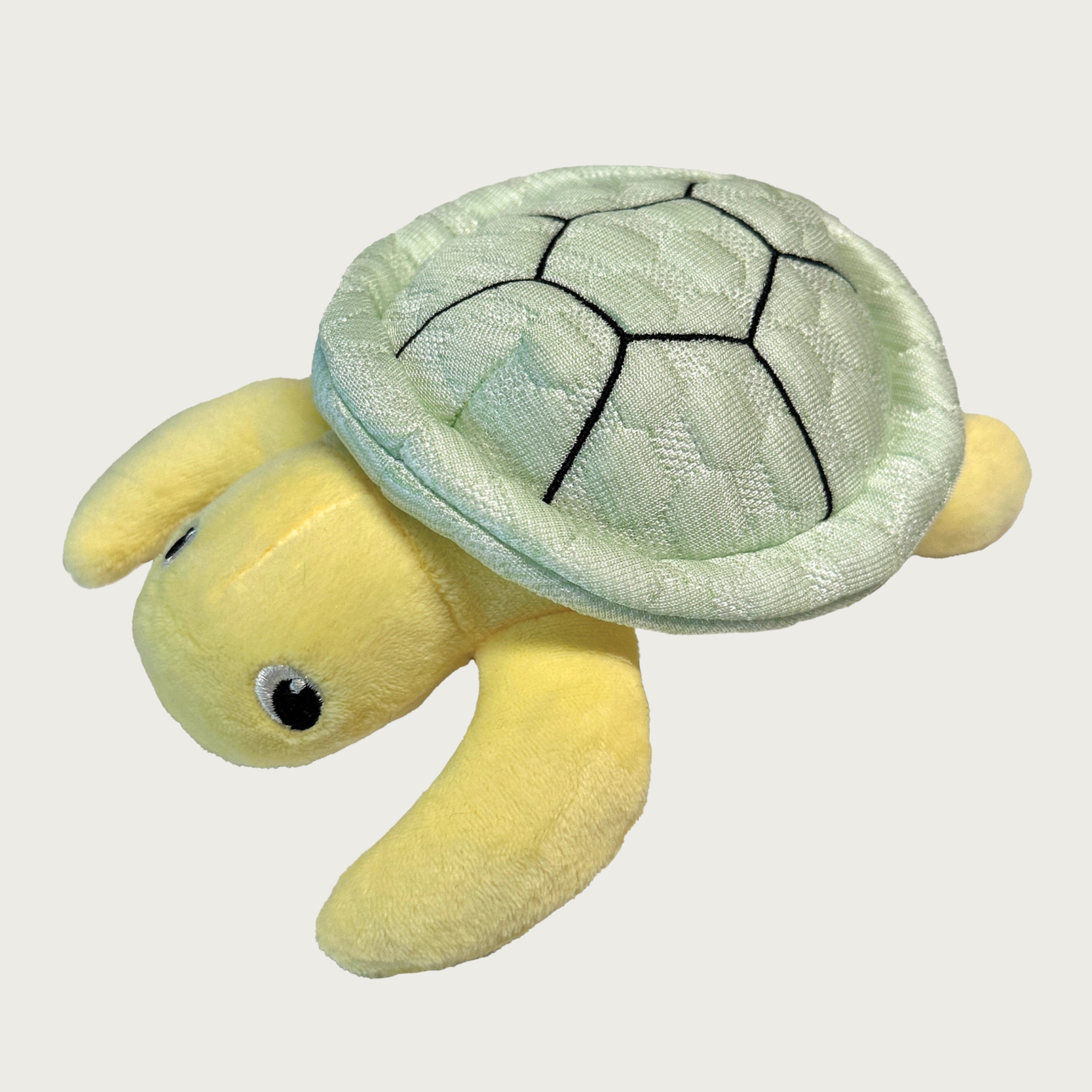 Dog toy shaped like a sea turtle, with a pale green quilted "shell" and pale yellow plush body, and embroidered eyes.