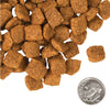 A close-up image of a handful of dry Chicken a la Veg kibble pieces, next to a dime for size comparison. 1-2 of the pieces would fit into the area of the dime. They have a slightly rounded square shape to them.