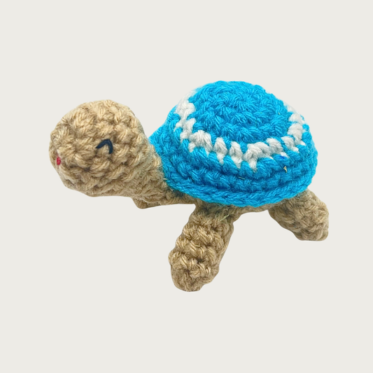 Crocheted Lil' Turtle cat toy with a tan body and a turquoise blue shell featuring a white circle and embroidered eyes & mouth.