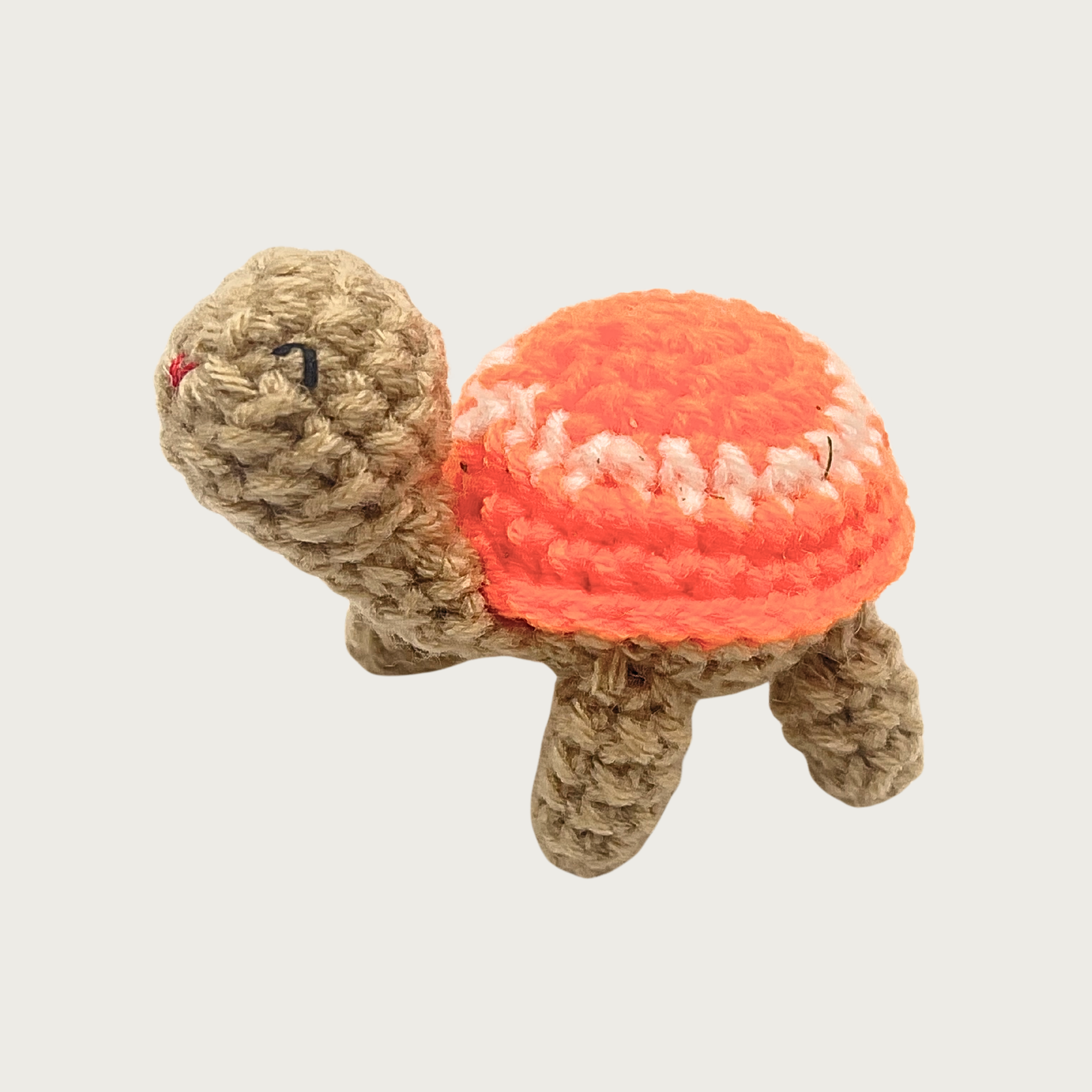 Crocheted Lil' Turtle cat toy with a tan body and melon-orange shell featuring a white circle and embroidered eyes & mouth.
