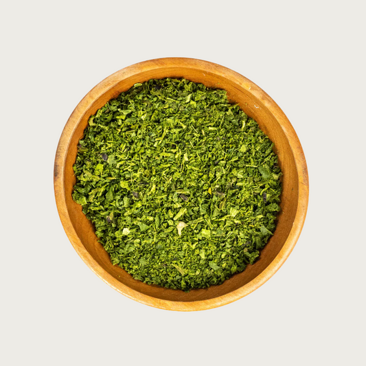 Wooden bowl filled with freeze dried Just Greens blend-coarsely chopped, bright green veggie flakes.