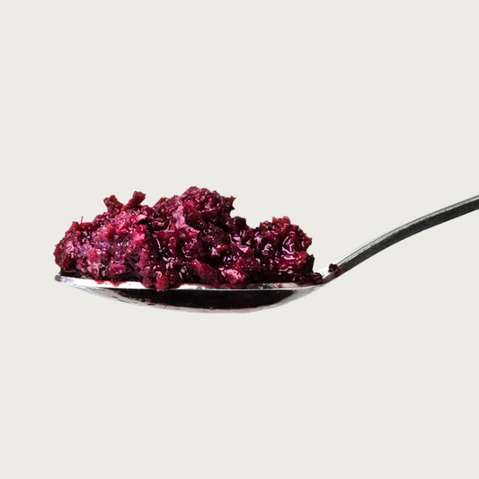 Close up of a spoon filled with Bam's Beets. It is coarsely chopped and burgundy in color.