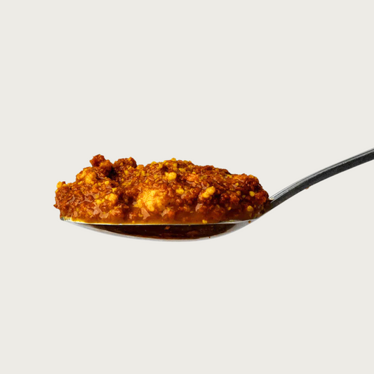 Close up of a spoon filled with Lua's Golden Paste. It is lumpy and brownish-orange in color.