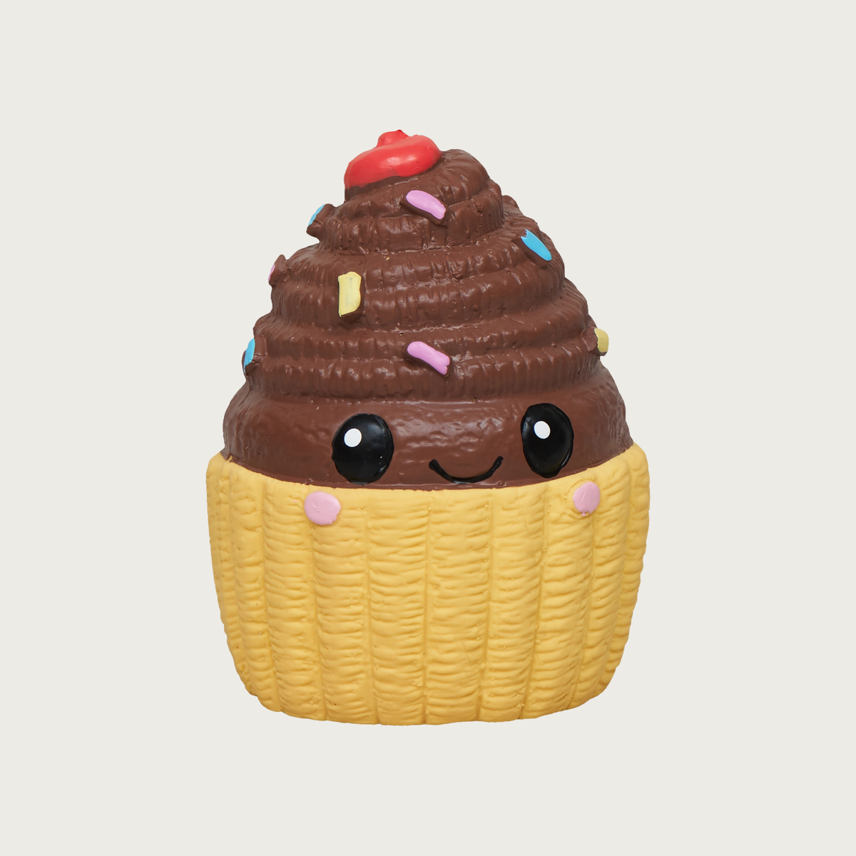 Mini latex cupcake dog toy. It has a light yellow base, with brown frosting on top. It has multi-colored sprinkles on the frosting, with a red cherry on top, and sweet, simple, smiley face in black, centered on the front.