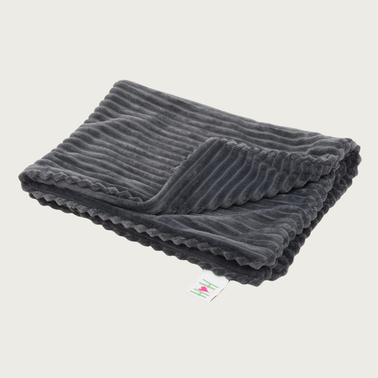 Folded wide-wale plush corduroy dark charcoal gray (with slight hint of dark blue) blanket with one corner folded back, and a Hugglehounds brand tag on the end.